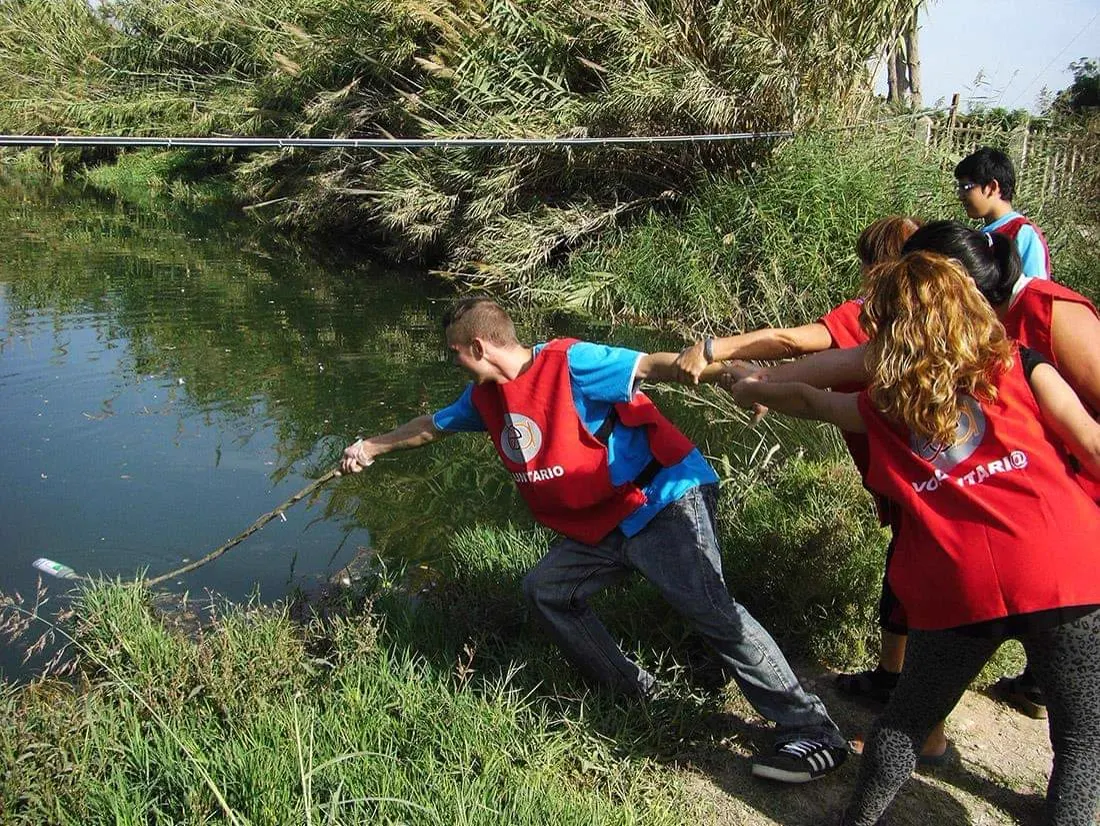 Voluntarios recogen basura en la orilla de un río