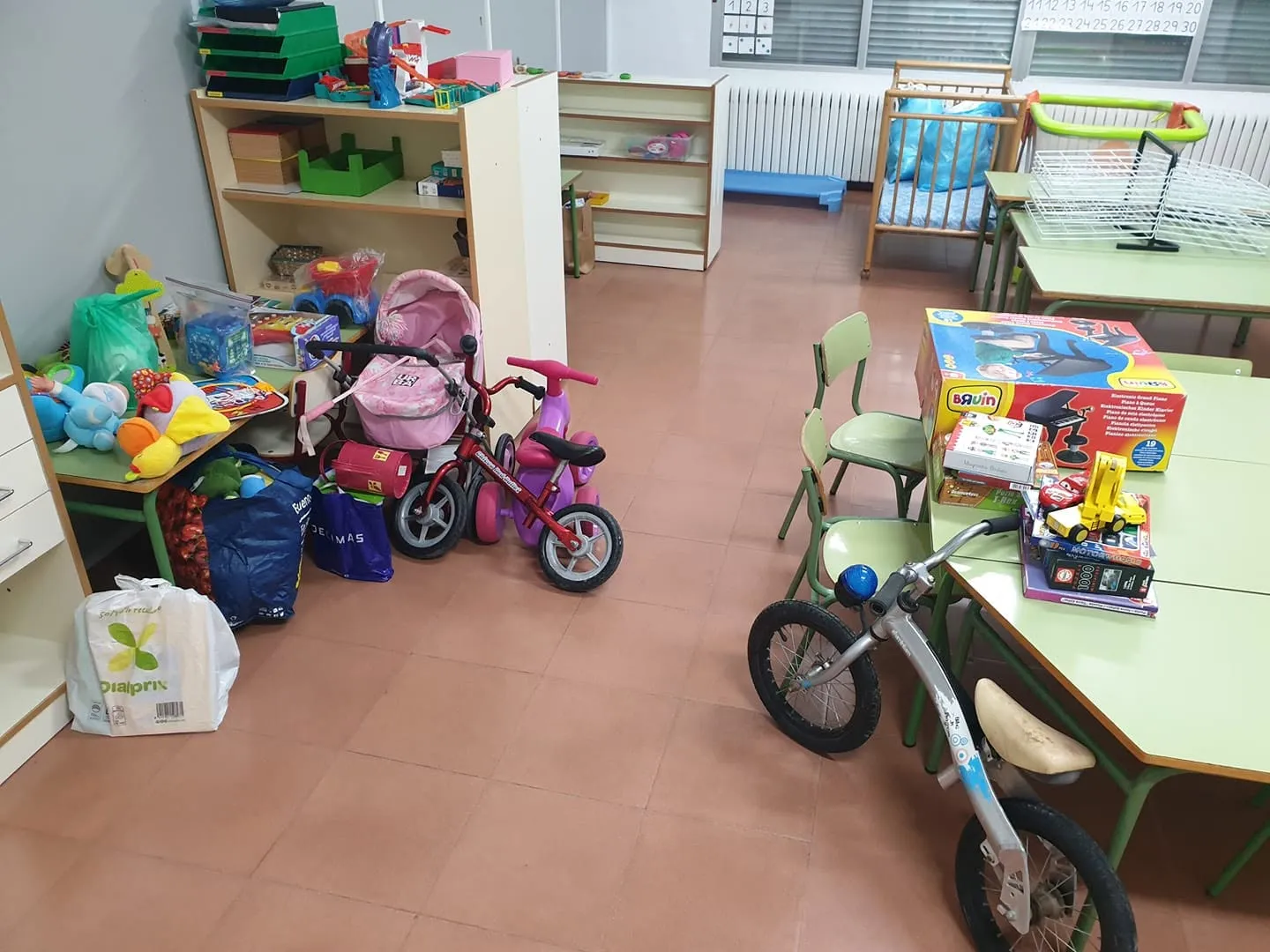 Juguetes, bicicletas y un carrito de muñecas donados, listos para repartir en un aula