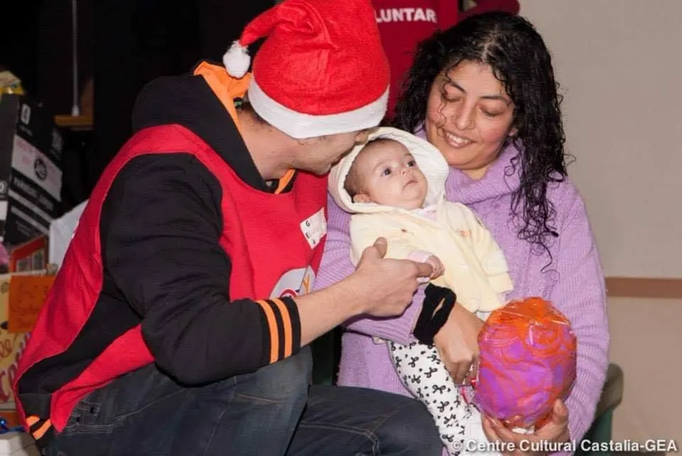 Voluntario con gorro de Papá Noel entrega un regalo